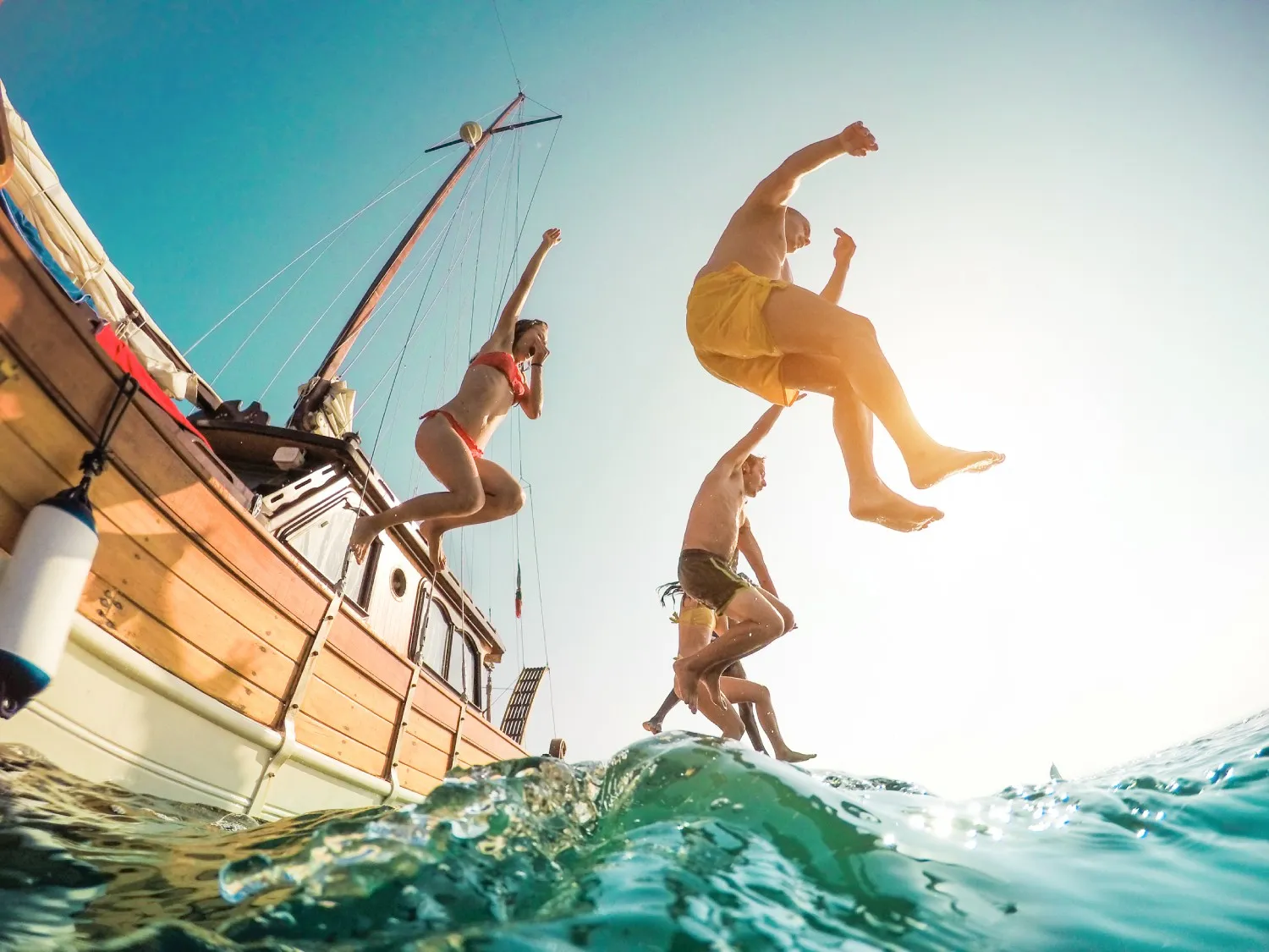 People travelling and jumping off a boat into water